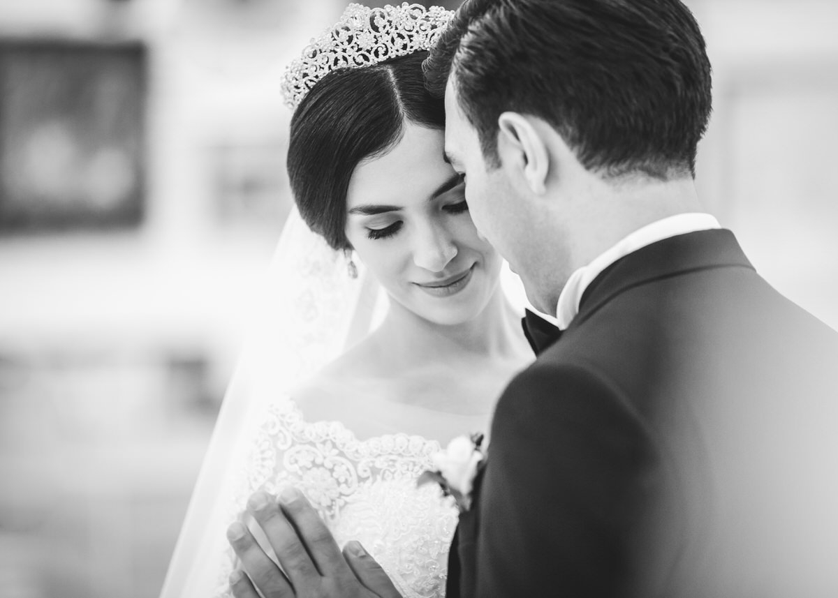 Brautpaar steht nah beieinander. Ihre Gesichter berühren sich fast. Sie halten ihre Hände aneinander. Sie trägt einen Schleier und ein Diadem. Ihr Blick geht nach unten. Fotografin: Claudia Nürnberger